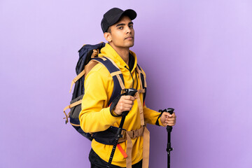 African American man with backpack and trekking poles over isolated background . Portrait