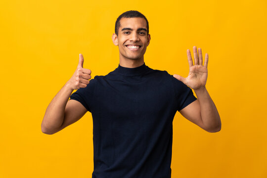 African American man counting numbres over isolated yellow background