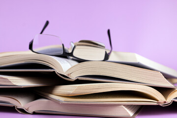 Opened books with glasses on pink background. Study, education and back to school concept.