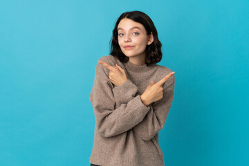 Teenager Ukrainian girl isolated on blue background pointing to the laterals having doubts