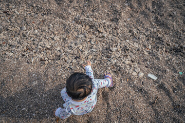 photo of child playing sand on the beach when mooring sun. The photos is perfect for poster, pamphlet and banner about holiday on the beach.