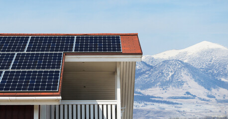 House roof with solar panels on a background os snowy mountains	