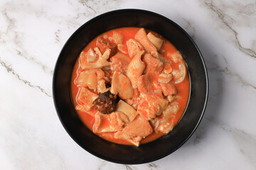 Ration of Madrid-style tripe on a black plate on a marble table