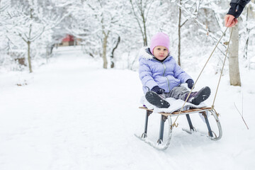 Fototapeta na wymiar A small child is sledding. Walk in the snowy park.