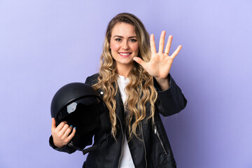 Young Brazilian woman holding a motorcycle helmet isolated on purple background counting five with...