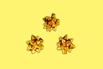 Gift golden bow with stars composition isolated on yellow background. Winter, sale and seasonal concept. Merry Christmas, New Year, celebration banner. flat lay, top view, space or place for text
