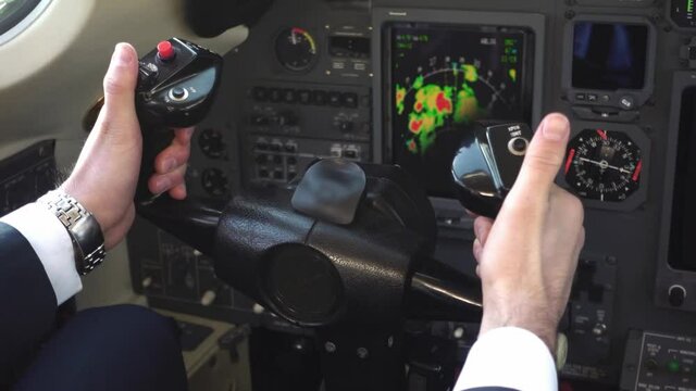 Hand of male pilot wearing suit controls yoke of private jet