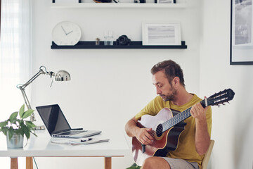 Man playing acoustic guitar at home.
