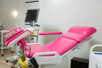 Photo of a pink gynecological chair in an equipped office of a modern medical clinic