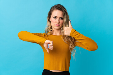 Young Brazilian woman isolated on blue background making good-bad sign. Undecided between yes or not