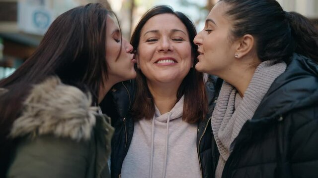 Mother and daughters kissing and hugging each other at street