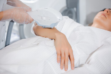 Close up laser hair removal on the arm of a young girl by a professional specialist in a modern cosmetology office