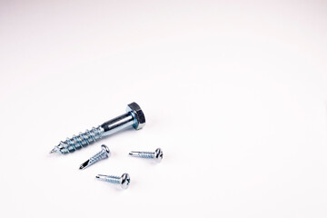 Three screws on a white background. A large screw and two small screws. Selecting a screw by size. Screw close up