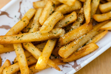 French fries on white marble dish on wooden background