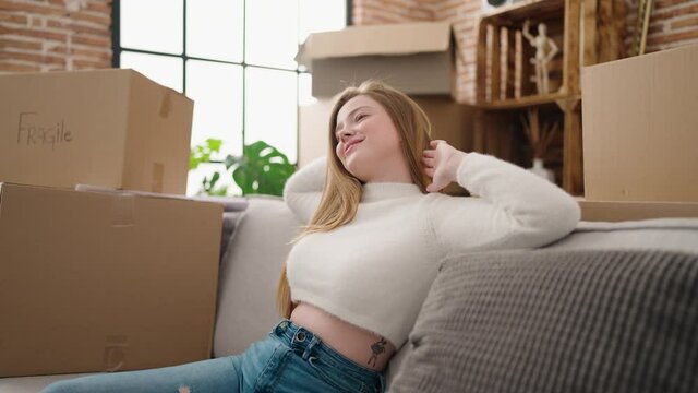 Young blonde woman smiling confident relaxed stretching arms at new home