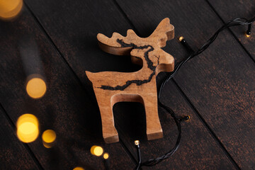Christmas Background with decorative wooden reindeer on  wooden rustic background. Wooden deer toy with bokeh lights.