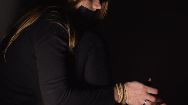 Woman is trying to free her hands and feets from rope. Human Trafficking. Domestic violence