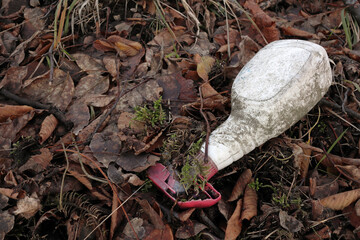 old soap spray dispenser among the leaves - environmental pollution