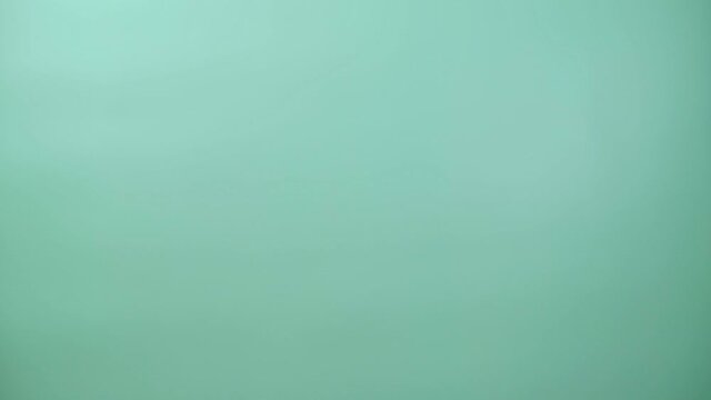 Yeti Bigfoot is peeking out of the scene. Loop video. Handmade crocheted toy. Surf green background. 4K