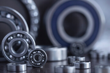 Set of deep groove ball and roller bearings on a gray background with soft focus. Axial chrome plated round bearings for heavy equipment and mechanical engineering close-up.