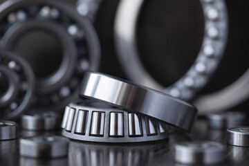 Fototapeta na wymiar Steel bearing set. Ball radial and tapered plain bearings for mechanical engineering, heavy equipment and machine tools close-up. Spare parts in the form of round bearings of different sizes.