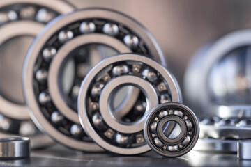 The concept of spare parts for mechanical engineering and modification of large heavy equipment in the form of ball bearings of different sizes, displayed in a row close-up. Steel bearings. - obrazy, fototapety, plakaty