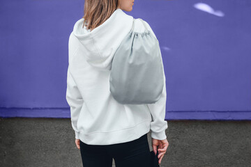 Modèle de pack cordon gris, maquette de sac pour chaussures de sport sur l& 39 épaule de la femme debout sur un fond violet ou très péri.