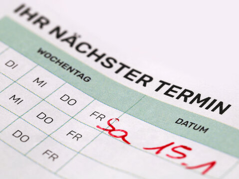 close up of pending doctor appointment on appointment card, medical concept image in german