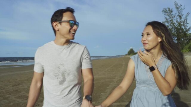 holidays, couple and family concept -portrait of young malaysian couple spending time together outdoor on beach