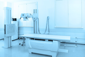 X-ray department in modern hospital. Radiology room with scan machine with empty bed. Technician adjusting an x-ray machine. Scanning chest, heart, lungs in modern clinic office.