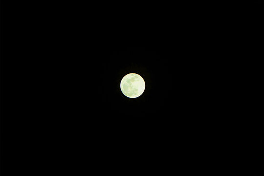 A distant photograph of the green moon on a full moon day. and the dark sky.