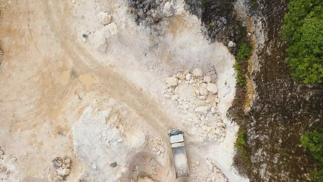 aerial footage excavator and truck work in limestone quarry. Heavy equipment in career.