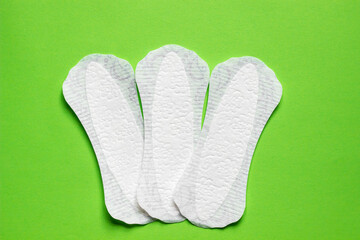 Feminine hygiene panty liner for menstruation. Menstrual cycle, pad. Green background.	Banner