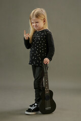 Studio portrait of little musician with her black guitar