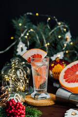 Fototapeta na wymiar Christmas coctail drink with grapefruit in shot glass at Christmas decoration. Selective focus