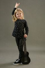 Studio portrait of little musician with her black guitar