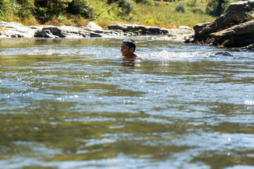 young village boy playing in the river full of water