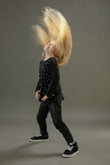 Studio portrait of toddler girl dancing and waving with her long blonde hair. Flying Hair.