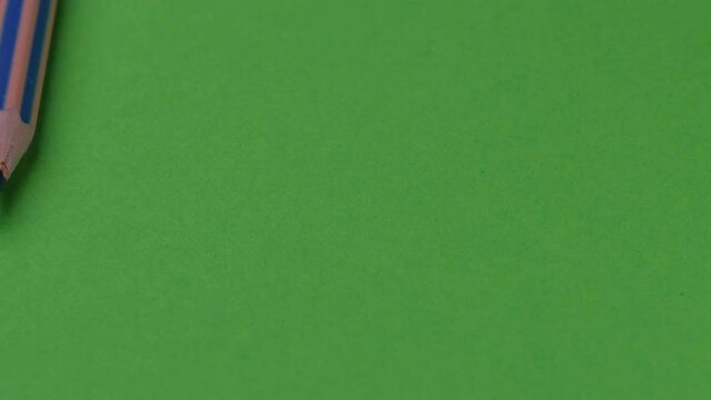 Colored pencils appear and line up on a green background, video clip, close-up