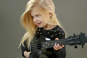 Fototapeta premium Studio portrait of adorable little girl playing ukulele 