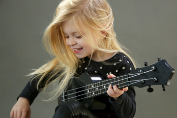 Fototapeta na wymiar Studio portrait of adorable little girl playing ukulele 