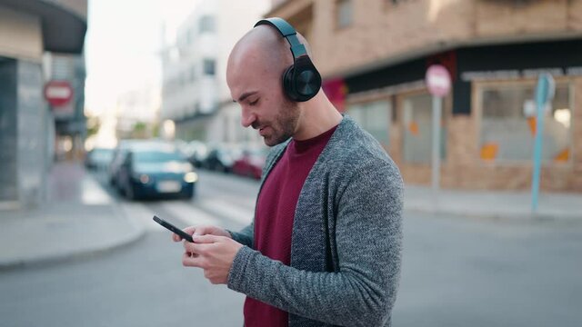 Young bald man smiling confident listening to music at street