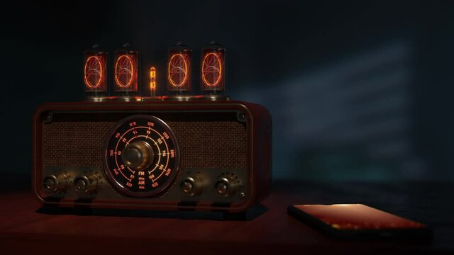 Vintage alarm clock with radio. The clock digits change from 23:59 to 00:00. Midnight. New Year has arrived. The radio turns on. On the phone, next to the clock on the screen lights up Merry Christmas