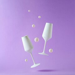 Two floating champagne flutes over a purple background