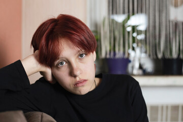 A pretty teenage girl with red hair is sitting in her room, she has problems communicating with...