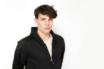 Sad teenager boy on a light background, the boy has black curly hair and a dark sports jacket. The...