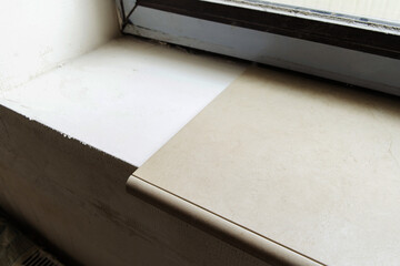 A fragment of a window sill laid with ceramic tiles. Indoor finishing work. Close-up