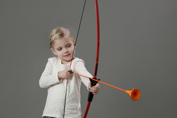 Studio portrait of 4 years old girl holding bow and arrow