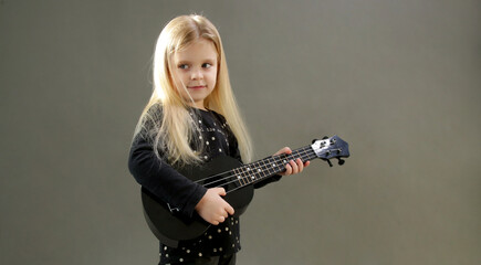 Studio portrait of adorable little girl playing ukulele	