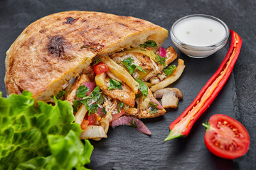 Giros. pita with inyushin meat, sauce and vegetables, on a dark background